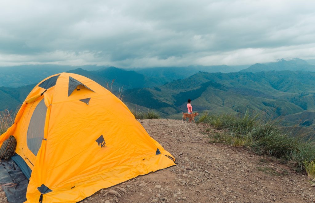 An image of a woman camping in Colorado mountains with her dog off-leash.